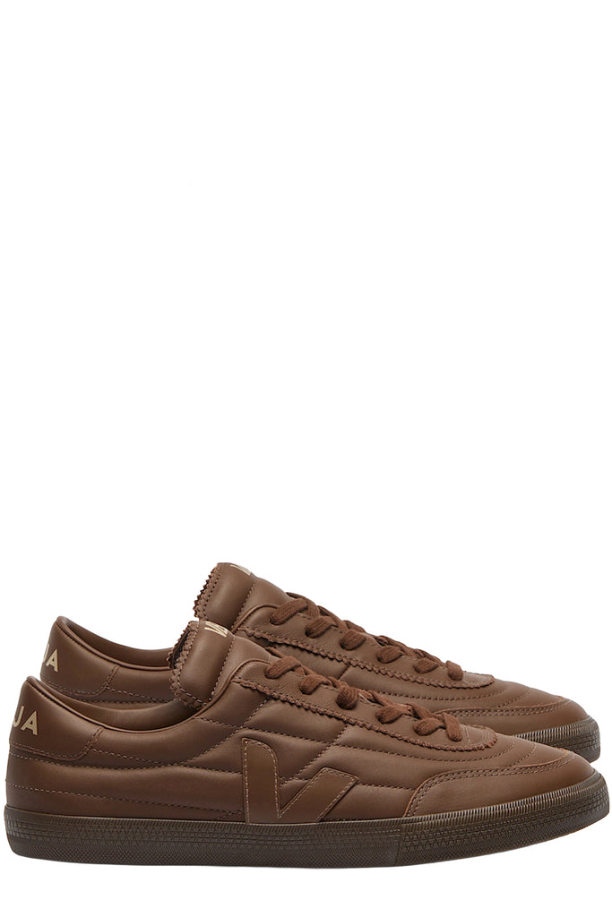 A pair of Veja sneakers in dark brown with seamlines made from leather shown against a plain white background.