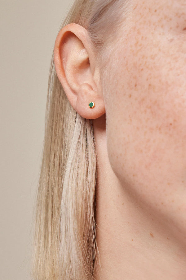 Model wearing the dot stud single earring in gold and petrol colour from the brand ENAMEL COPENHAGEN